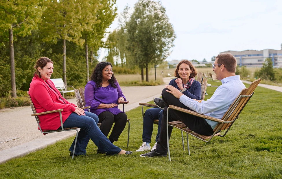 Four business people discussing while sitting in a park in the Novartis Basel campus