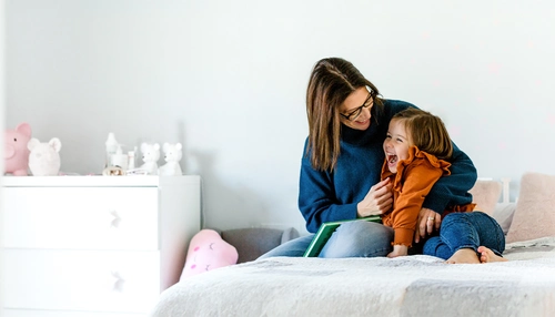 Mother and daughter cuddling on a bed in a kids room