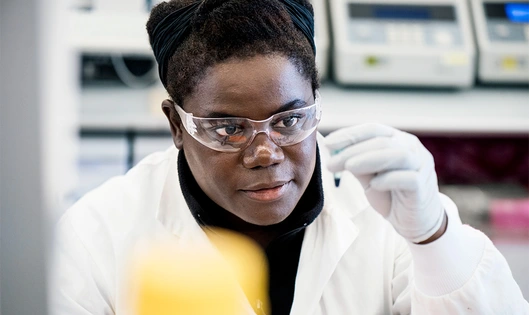 A female research scientist in a lab looking at a sample